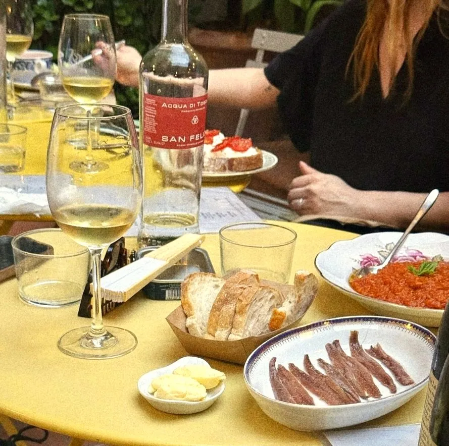 Anchovies, bread and butter on a yellow table with white wine