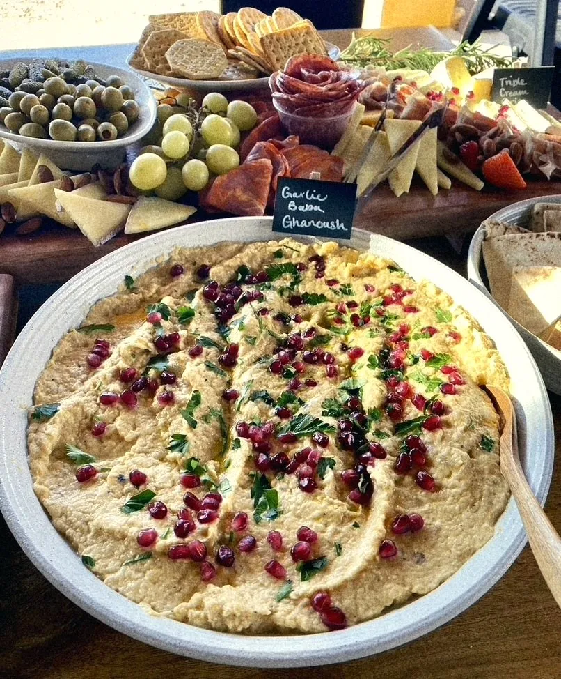 Garlic baba ghanoush with pomegranate and parsley in a speckled bowl
