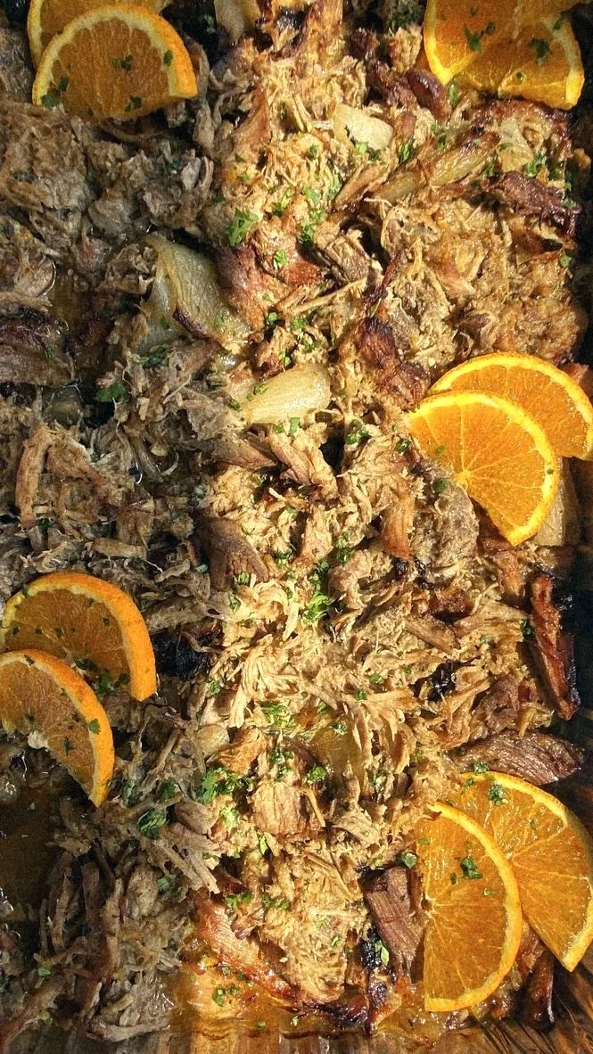 A tray of slow-roasted pulled pork with orange slices