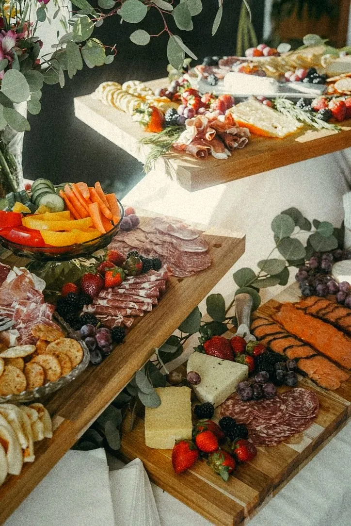 Tiered boards of cured meats, cheese and berries with eucalyptus