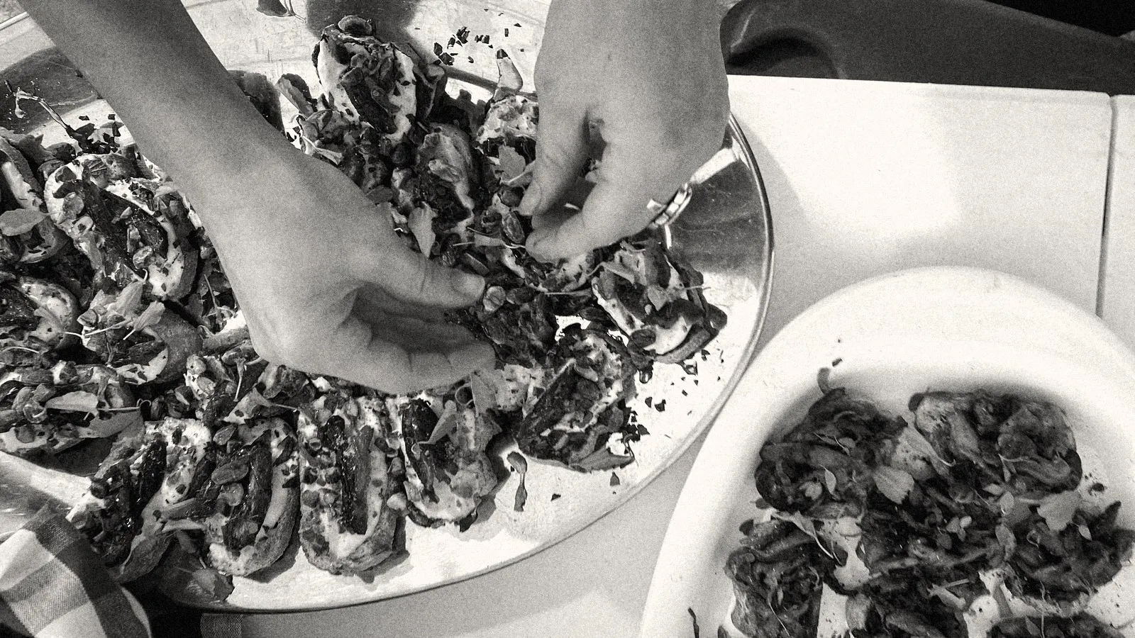 Hands finishing ricotta, date and pistachio crostini with marigold petals