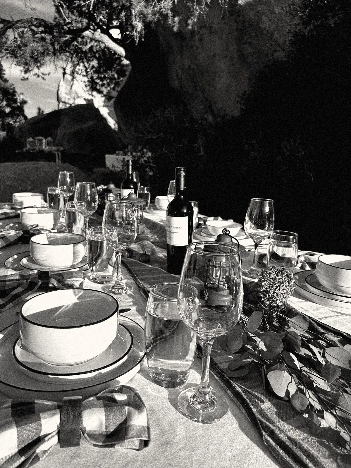 Table setting in the desert: stacked plates, wine, lanterns and a rust runner
