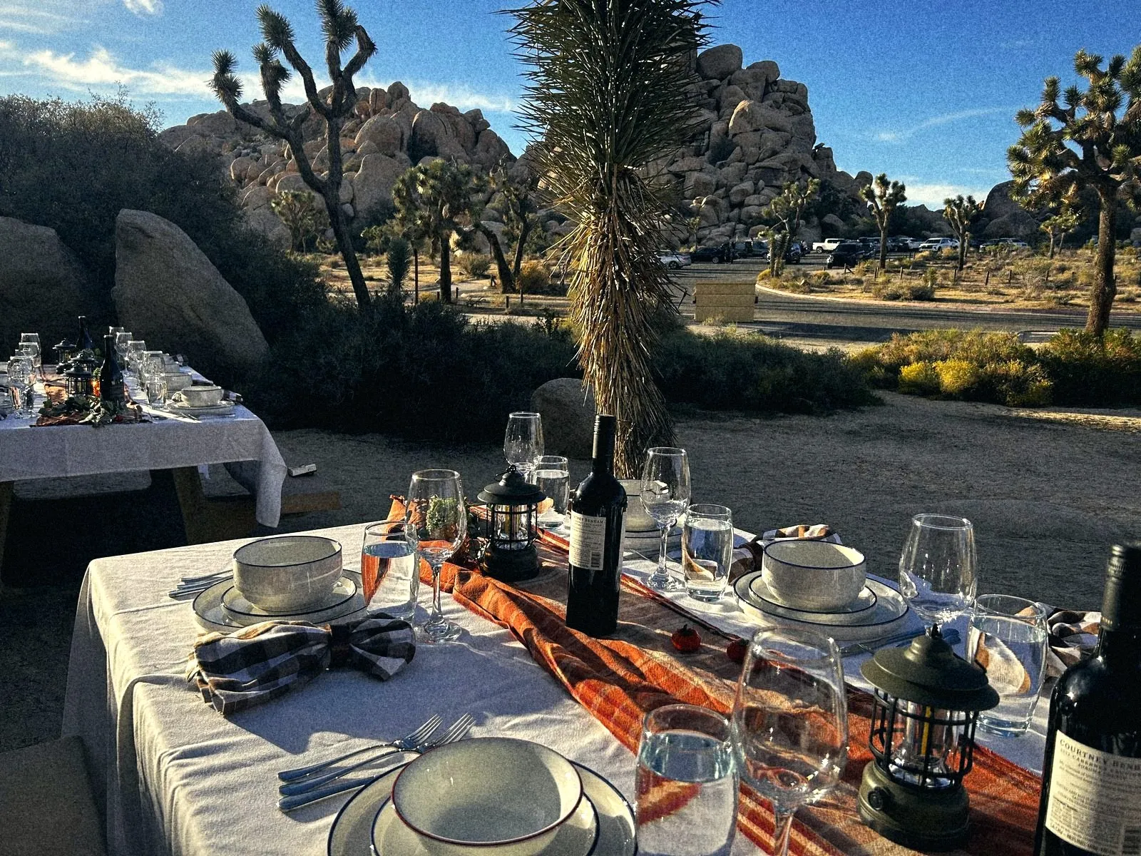 A long table set among the boulders and Joshua trees at golden hour