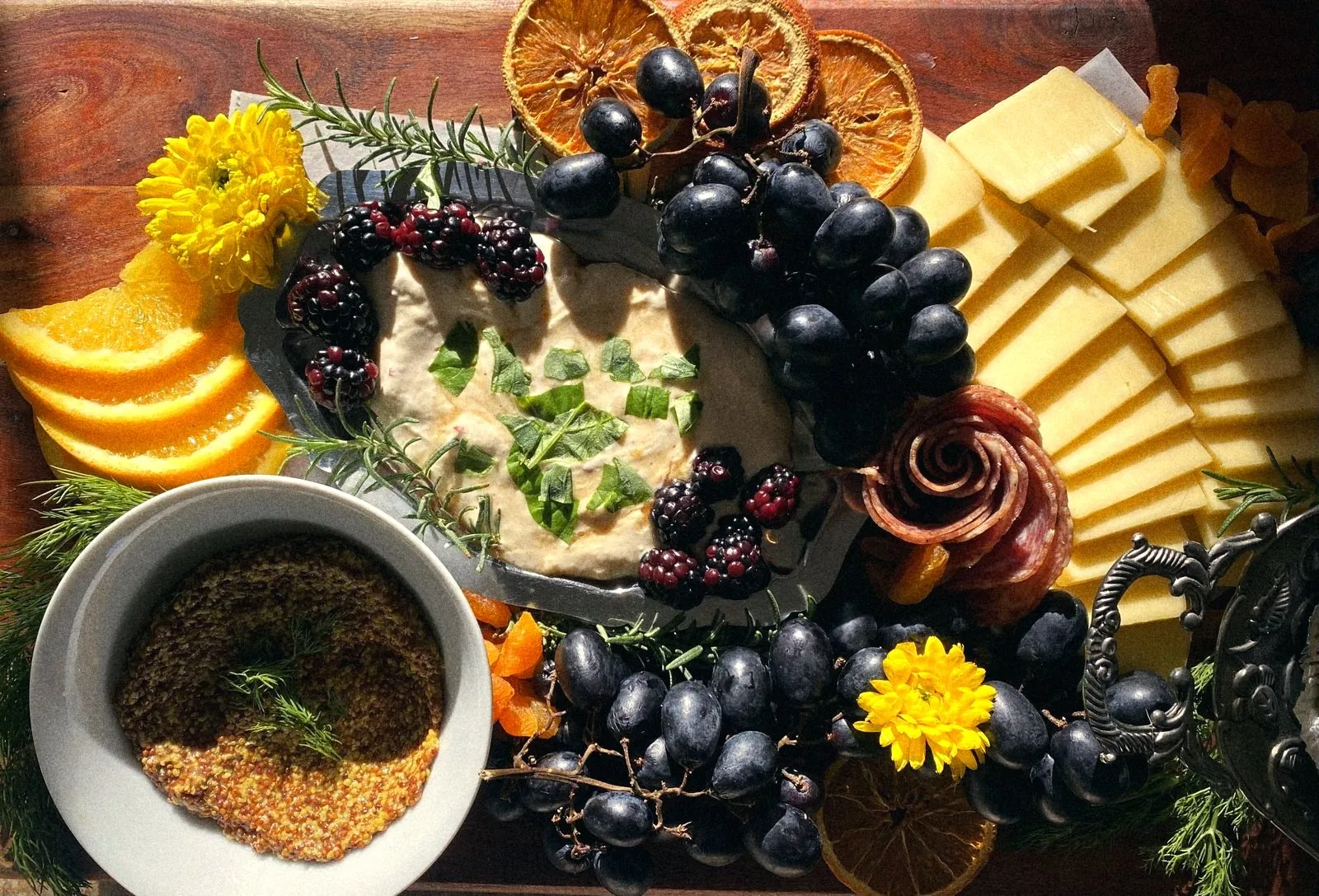A board of whipped ricotta with blackberries, cheeses, salami roses and dried oranges