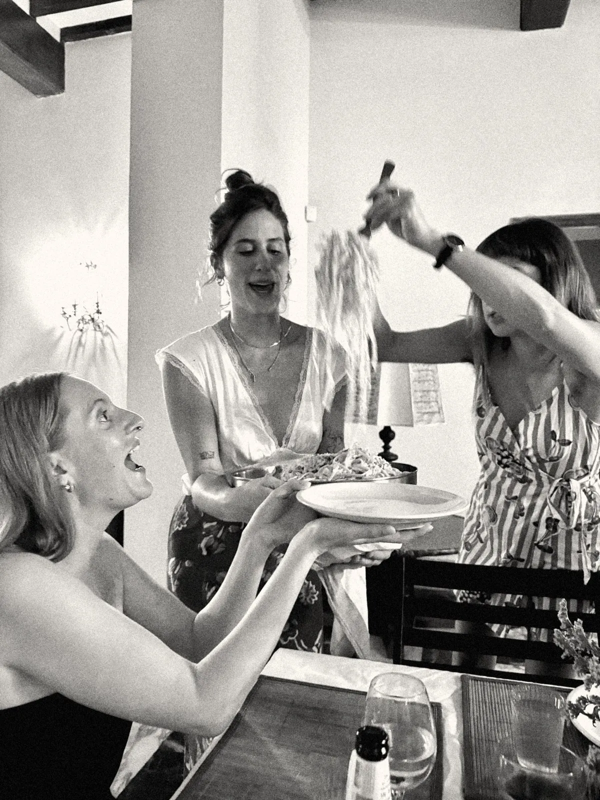 Kristi serving fresh pasta to a delighted guest at a dinner party