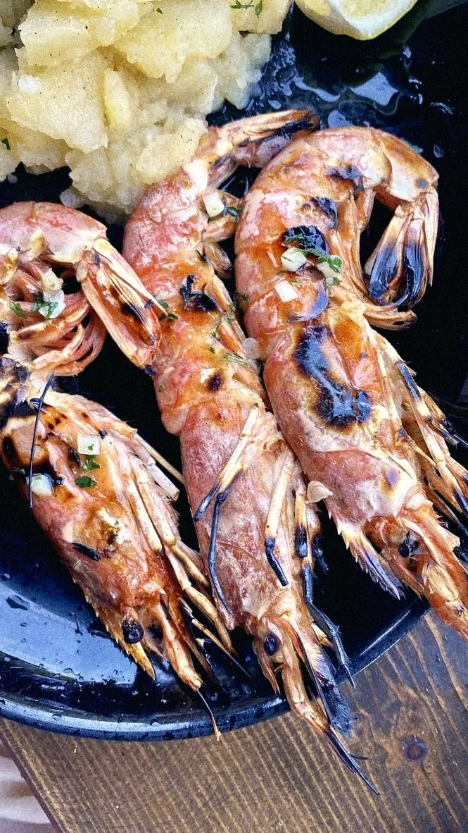 Grilled head-on prawns on a black plate