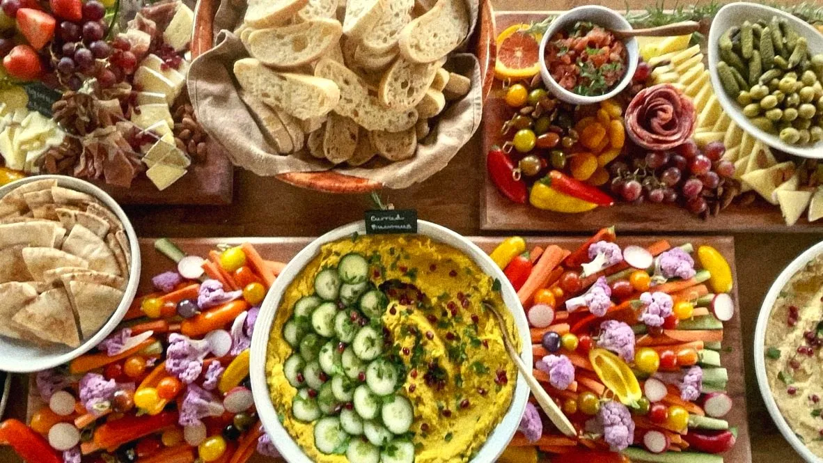 A full spread from above: bread, crudité, curried hummus, cheeses and pickles