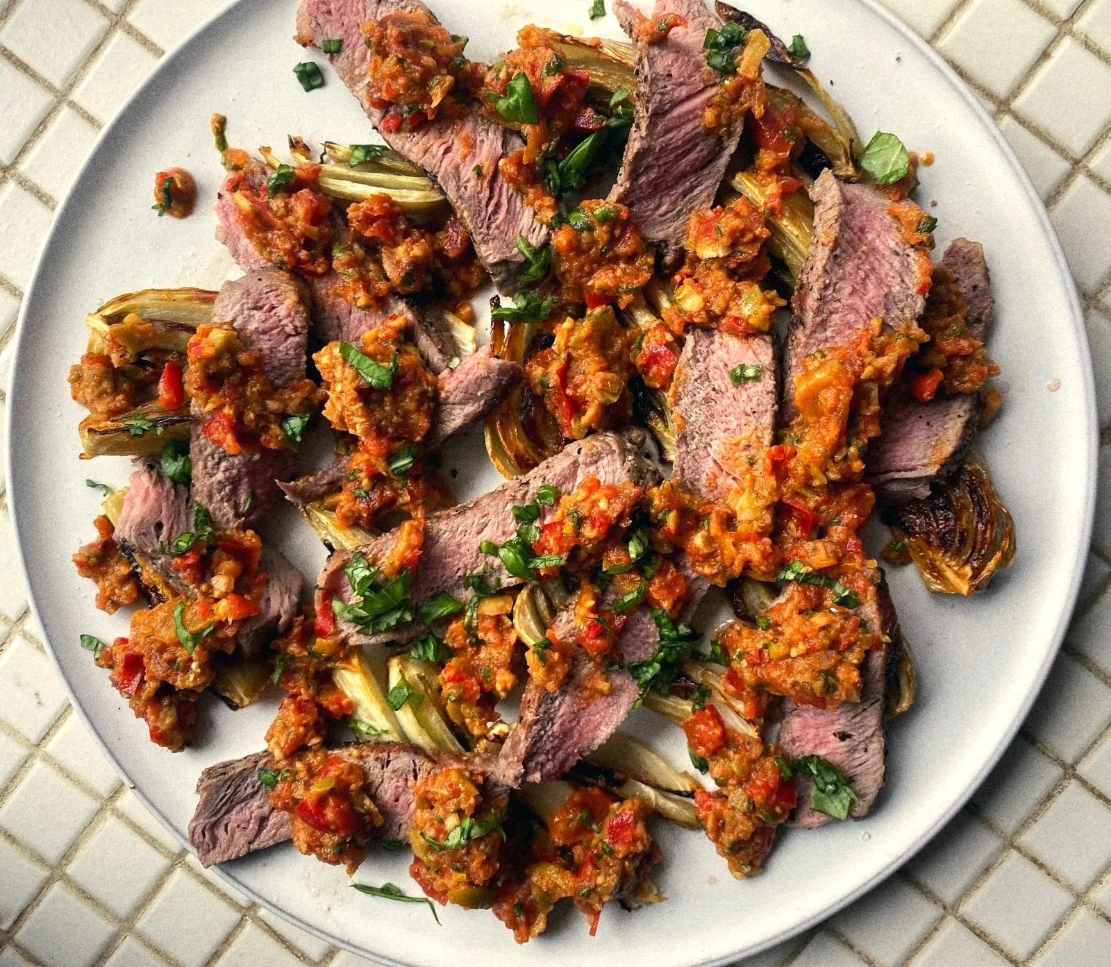 Sliced steak over roasted fennel with a chopped pepper salsa