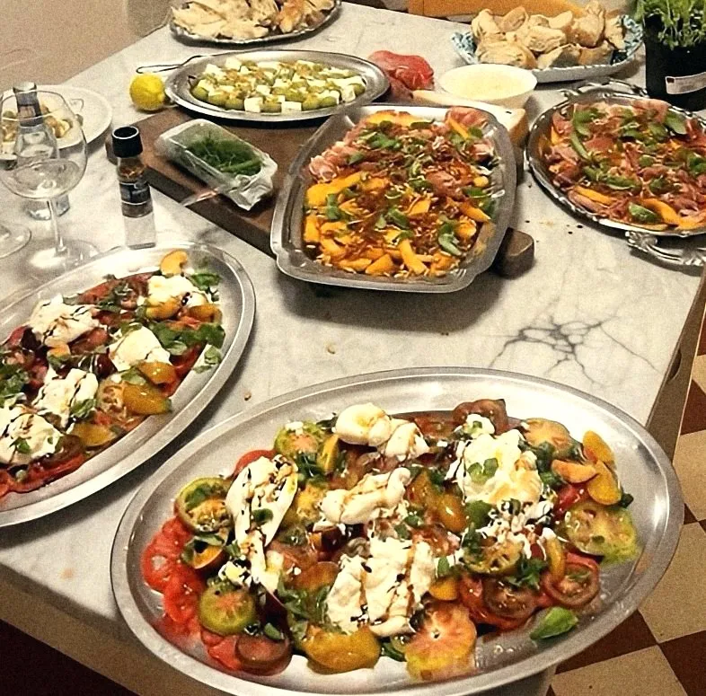 Platters of heirloom tomatoes with burrata and basil on a marble counter